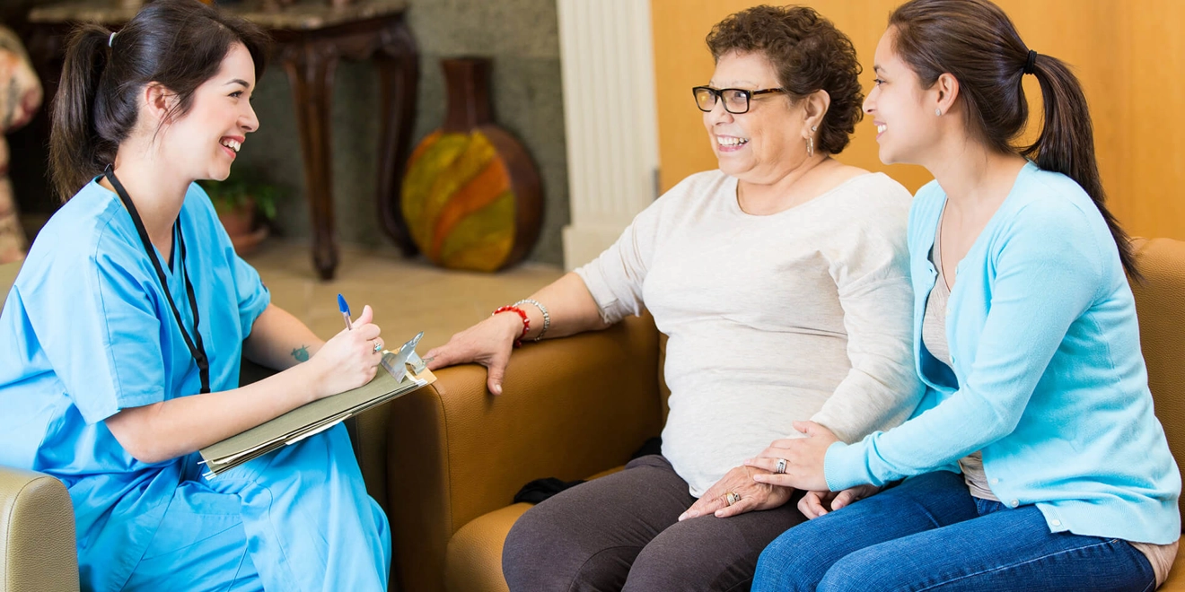 Female doctor dressed in scrubs talking to a female patient and her daughter