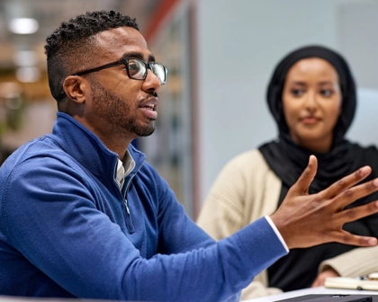 A black male employee and black female employee in the office having a discussion.