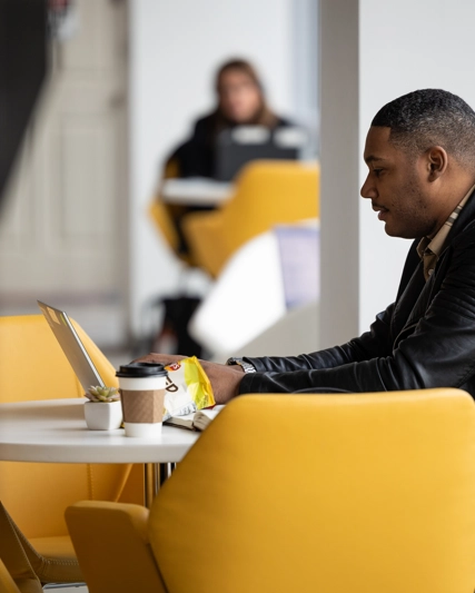 An employee working on his laptop in the office cafe