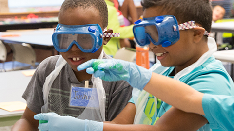 Children wearing goggles working on a science experiment