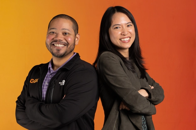 two employees with an orange back drop.