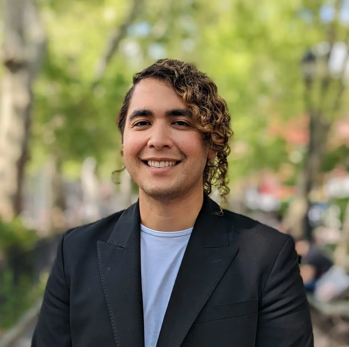 Photo of Kevin smiling at the camera wearing a white shirt and black blazer