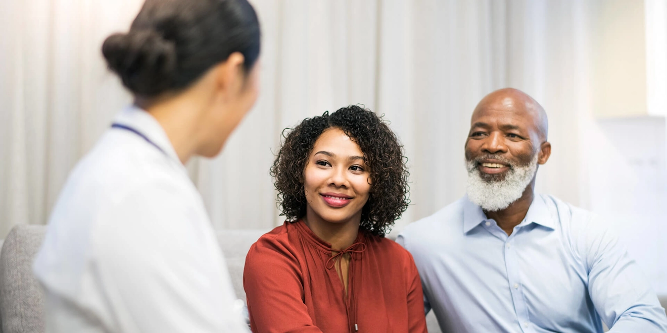 Female doctor speaking with a man and a woman in an office